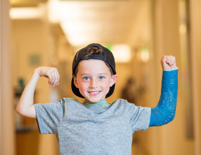 Little boy in a cast shows off his strength