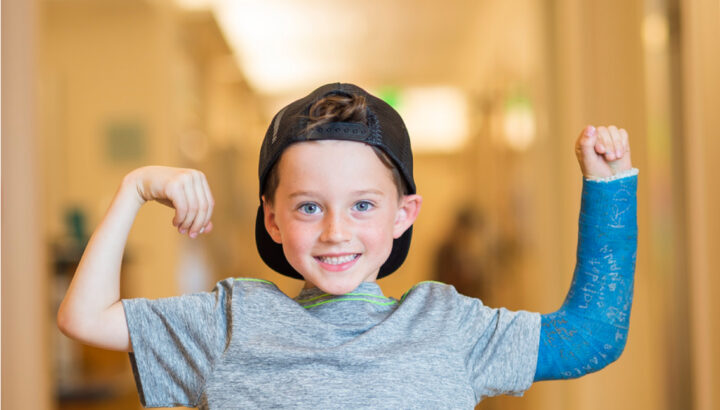 Little boy in a cast shows off his strength