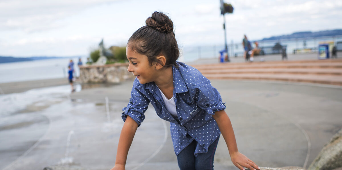 Young girl climbs on rocks at a park in Tacoma.