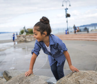 Young girl climbs on rocks at a park in Tacoma.