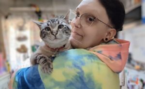 Picture of a young person in a tie-dyed sweatshirt holding a cat