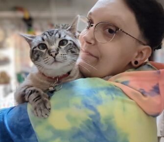 Picture of a young person in a tie-dyed sweatshirt holding a cat