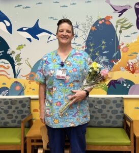 Pediatric nurse McGlinchy poses with flowers after accepting The DAISY Award.