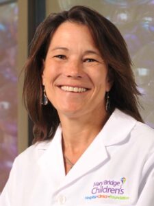 Portrait of Dr. Chris Ladish wearing a white coat with a Mary Bridge Children's Hospital logo embroidered on it.