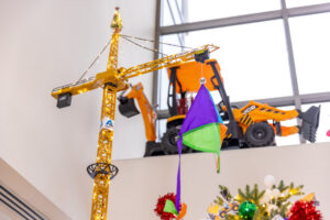 Construction toy crane hoists a Mary Bridge Children's flag above a construction themed Christmas tree.