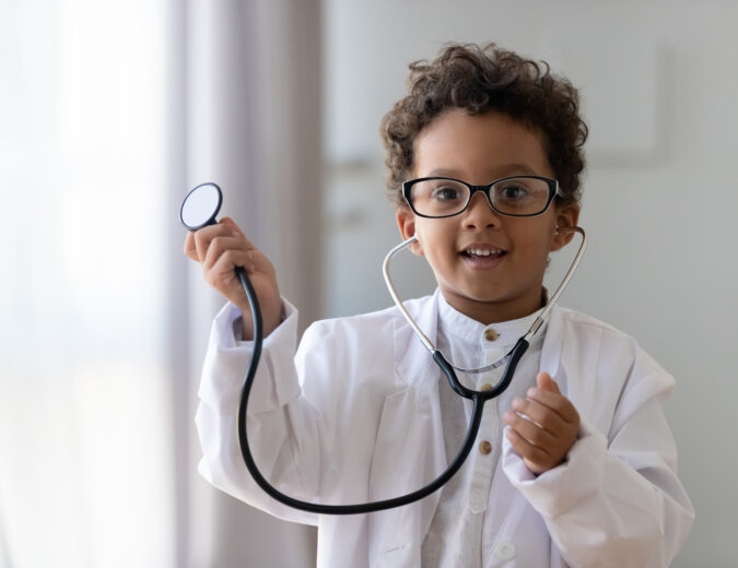 Young boy is dressed as a doctor and posing with a stethoscope