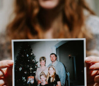 Woman holding up an old family photo.