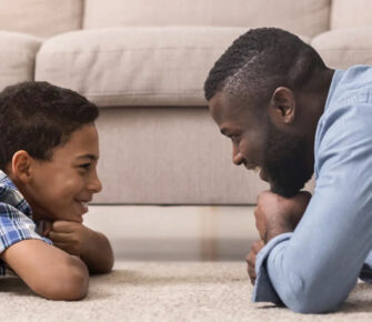 Son and father laying on the floor together.