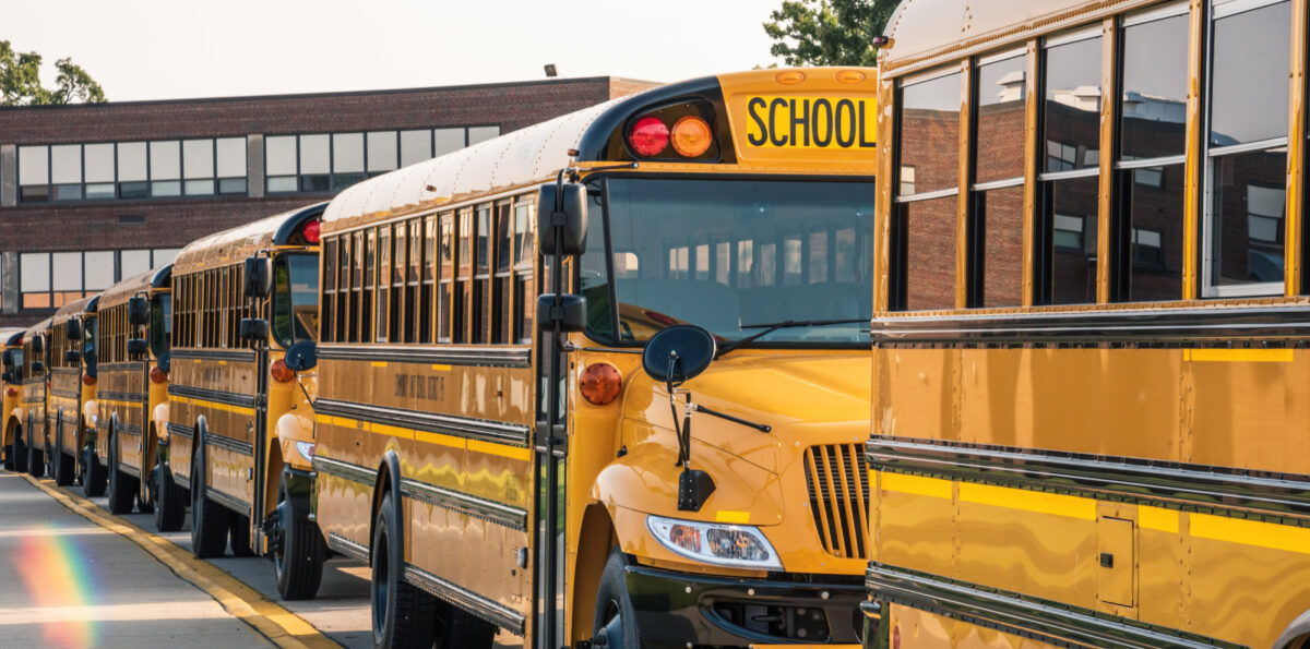 Yellow buses lined up in front of school ready to pick up kids.