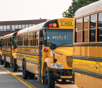 Yellow buses lined up in front of school ready to pick up kids.