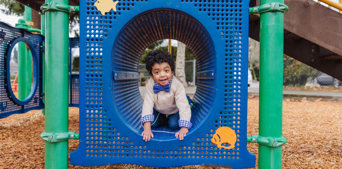 3-year-old Carlos, wearing a bow tie, plays in a playground structure