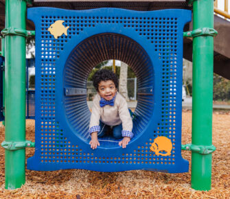 3-year-old Carlos, wearing a bow tie, plays in a playground structure