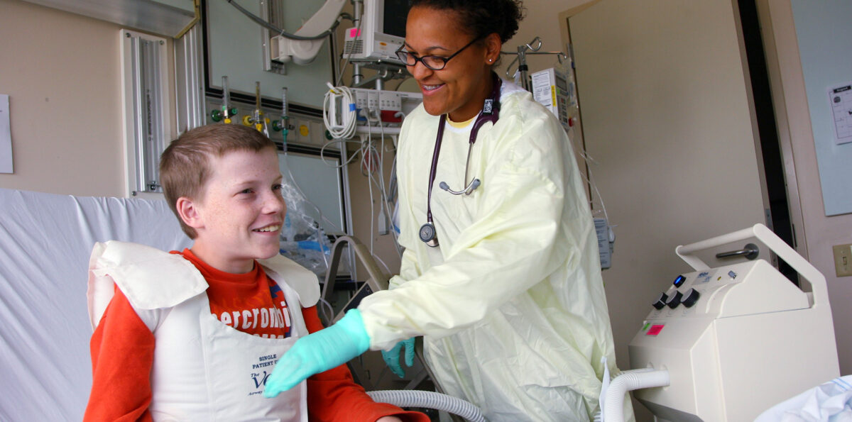 Young patient wears a Cystic Fibrosis while being attended to by a health care provider.