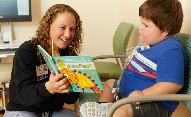 Child life specialist reads to a young patient