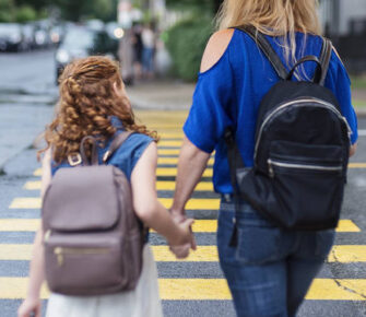 Mother and child holding hands walking to school.