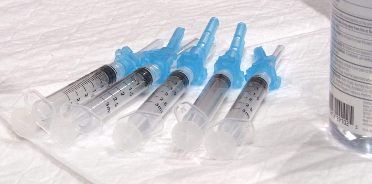 Syringes with COVID-19 vaccine sit on a table.