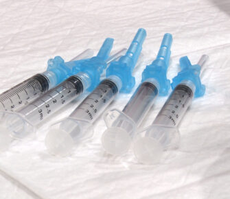 Syringes with COVID-19 vaccine sit on a table.