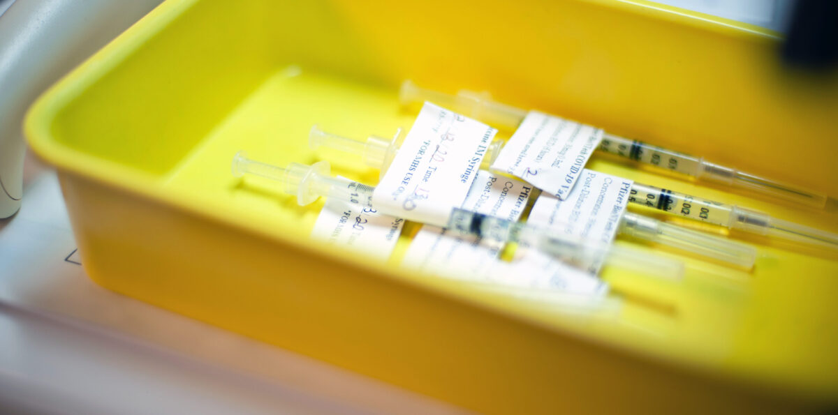 Yellow plastic tray with Covid-19 Pfizer vaccine syringes.