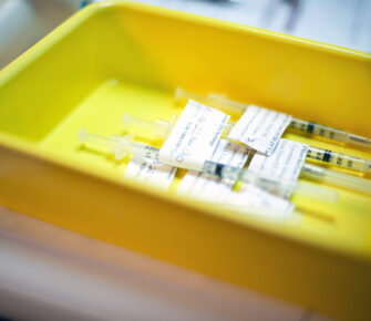 Yellow plastic tray with Covid-19 Pfizer vaccine syringes.