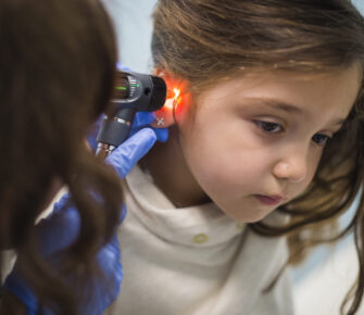 Young girl having her ear examined with an otoscope.