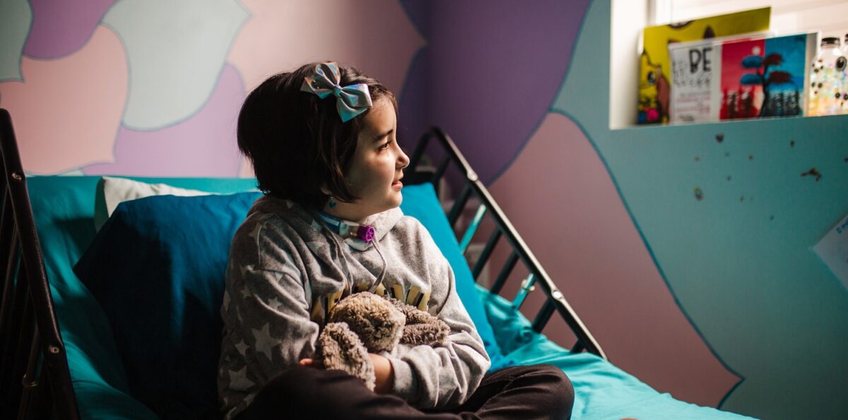 Mary Bridge Children’s Patient Ambassador Evangeline sits on her hospital bed.