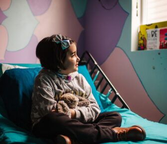 Mary Bridge Children’s Patient Ambassador Evangeline sits on her hospital bed.