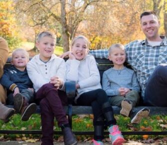 Family sitting on a bench in a park.