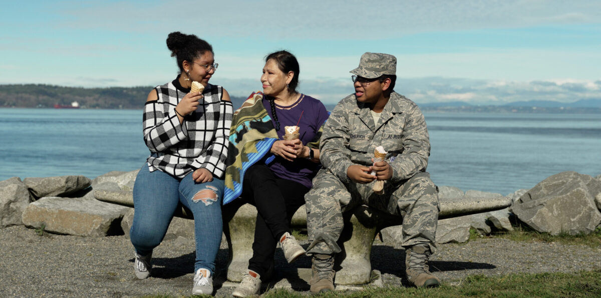 Family sitting on together near the water.