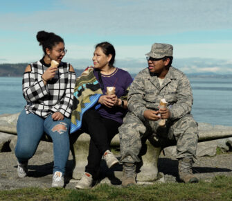 Family sitting on together near the water.