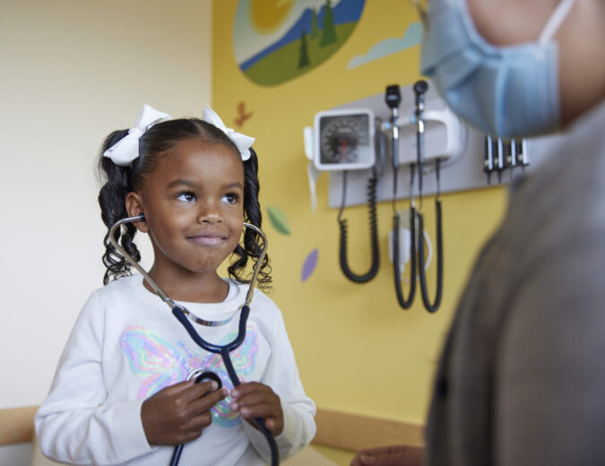 Little girl at doctor's appointment, holding stethoscope