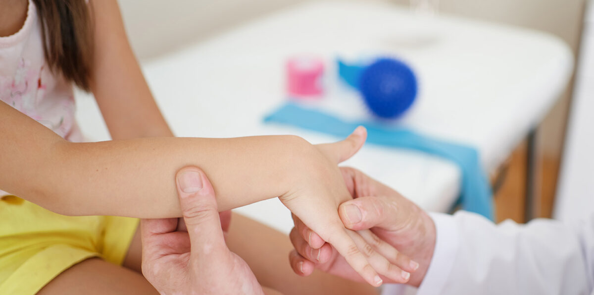 Wrist massage. A male massage therapist puts pressure on a sensitive point on a kid's hand.