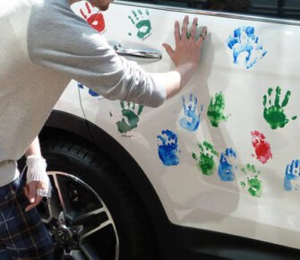 Kids putting hand prints on car.