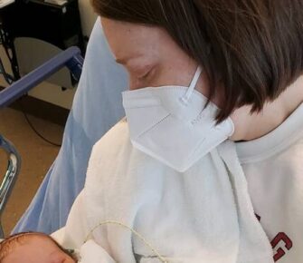 Mother wearing a mask looking at her new born.