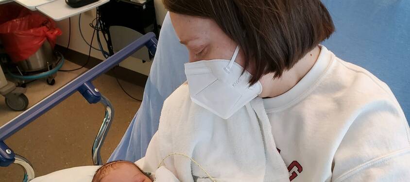 Mother wearing a mask looking at her new born.