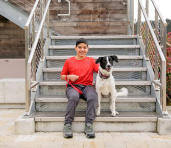 James sits on the steps with his dog.