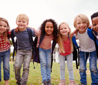 Excited elementary school pupils on playing field at break time.