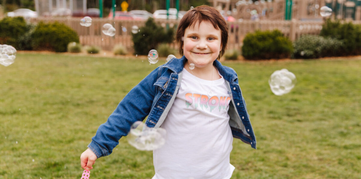 Lilith Kahn runs in a field with soap bubbles around her.