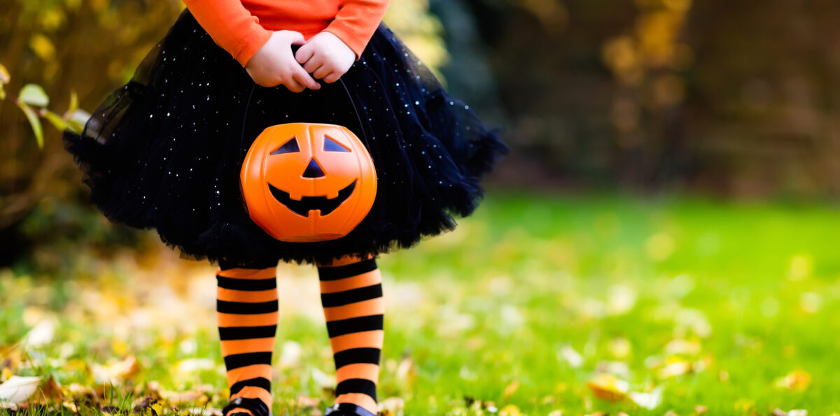 Little girl in witch costume playing in autumn park.