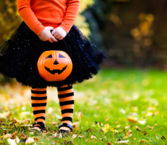 Little girl in witch costume playing in autumn park.