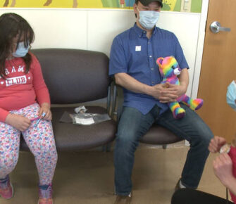 Children sitting with father in a medical waiting room.