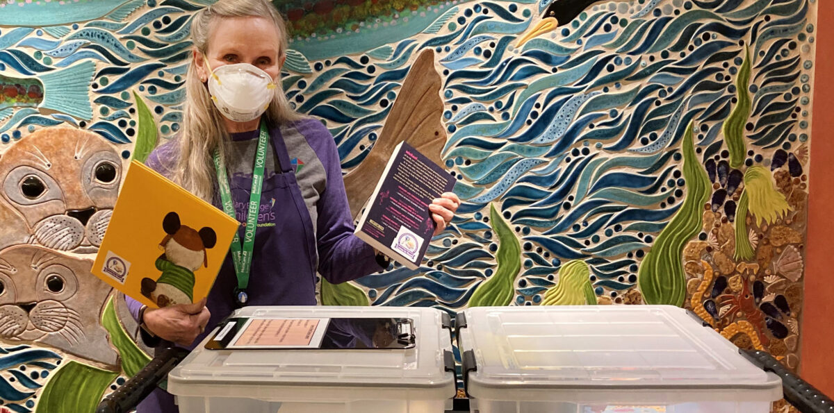 A volunteer with teh Loves to Read program displays books.