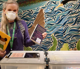 A volunteer with teh Loves to Read program displays books.