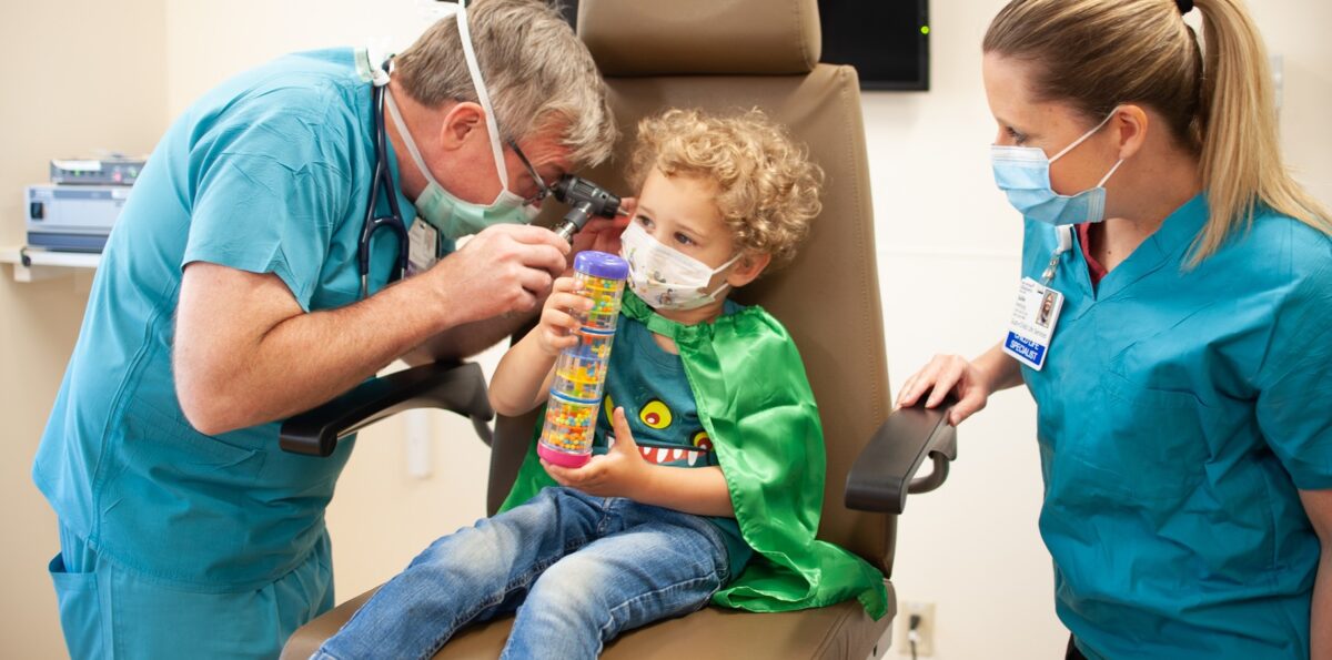 Child in green cape being examined at the ENT clinic at Mary Bridge Children's Outpatient Center.