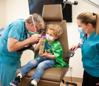 Child in green cape being examined at the ENT clinic at Mary Bridge Children's Outpatient Center.