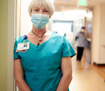 Woman in medical scrubs wearing a mask.