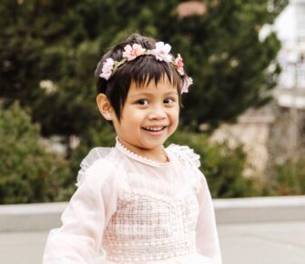 Little girl with flowers in her hair smiling.