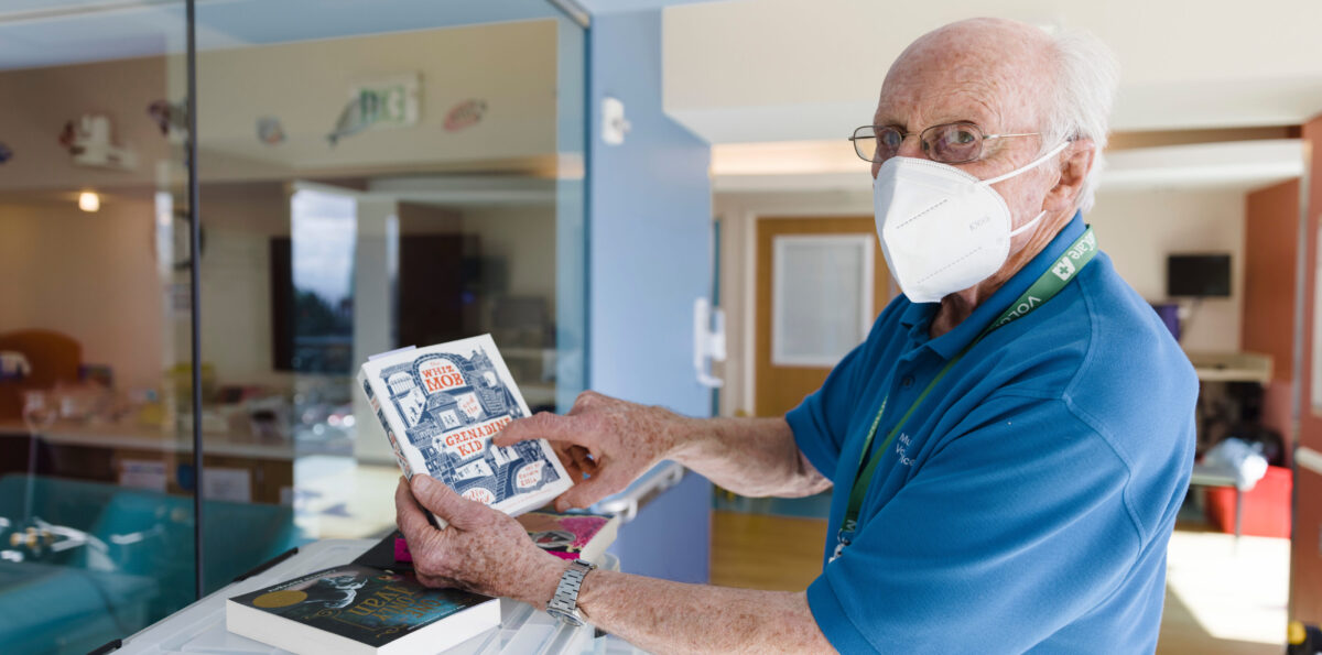 Volunteer Peter Norman points out the title of a book he's holding.