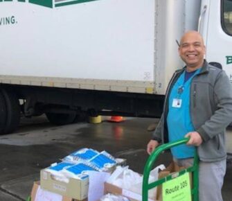 Man standing in front of a truck posing with donations.