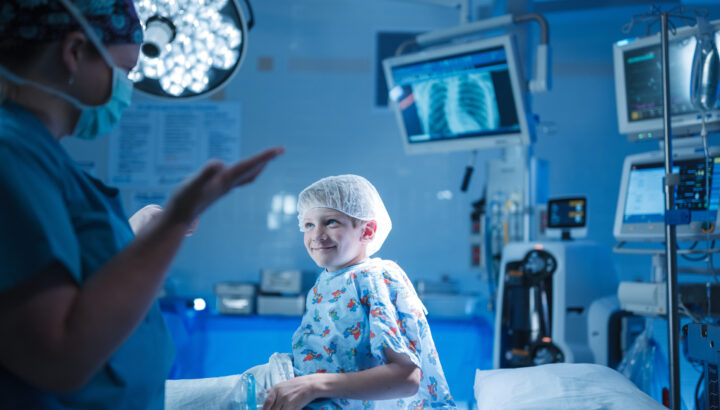 Boy smiles while talking to surgeon in operating room.